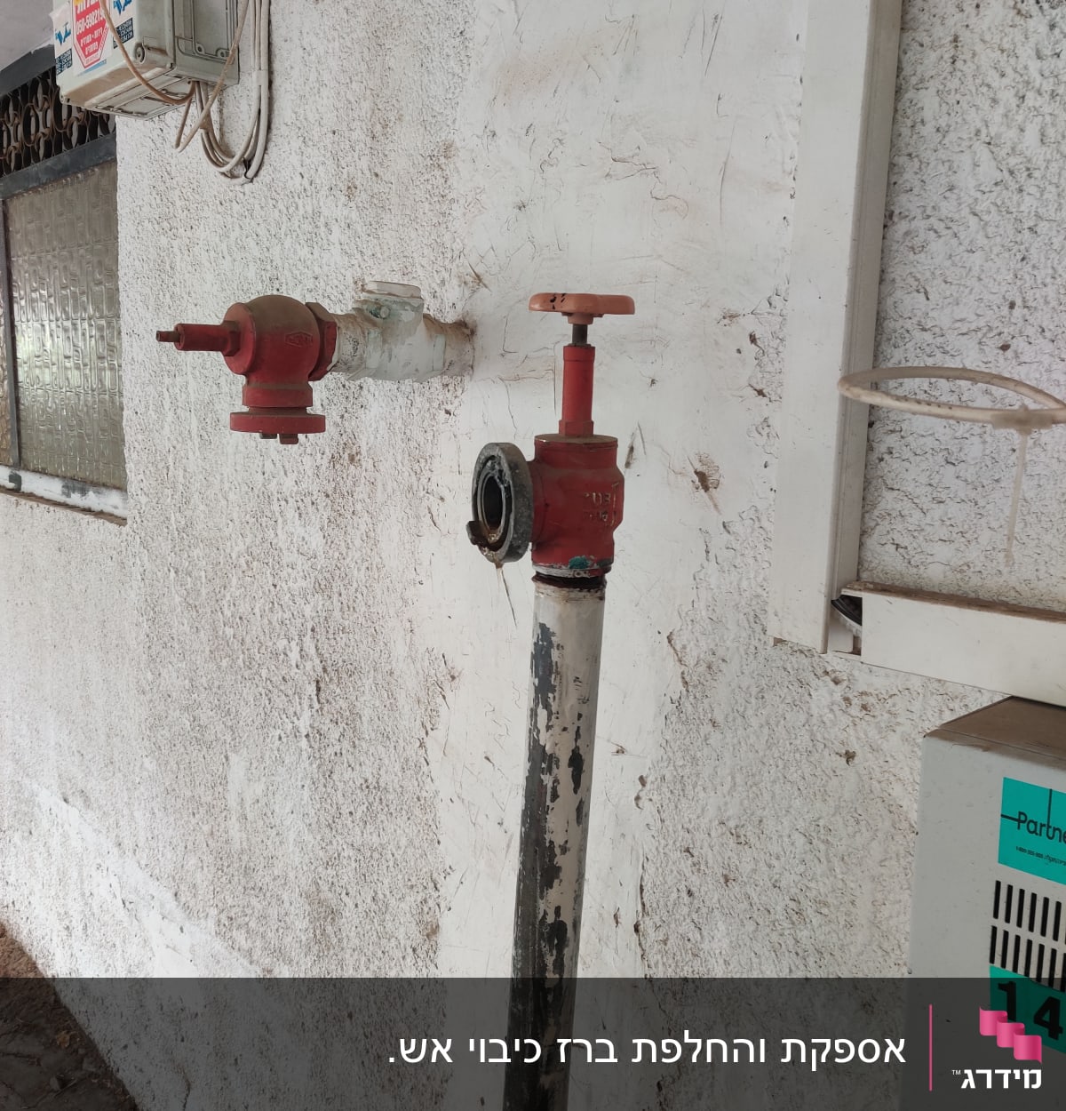 ברז מים אדום על קיר לבן עם צינור